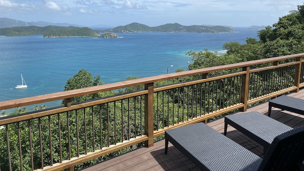 Una terrazza con ringhiera che si affaccia su un corpo d'acqua, con barche visibili in lontananza.