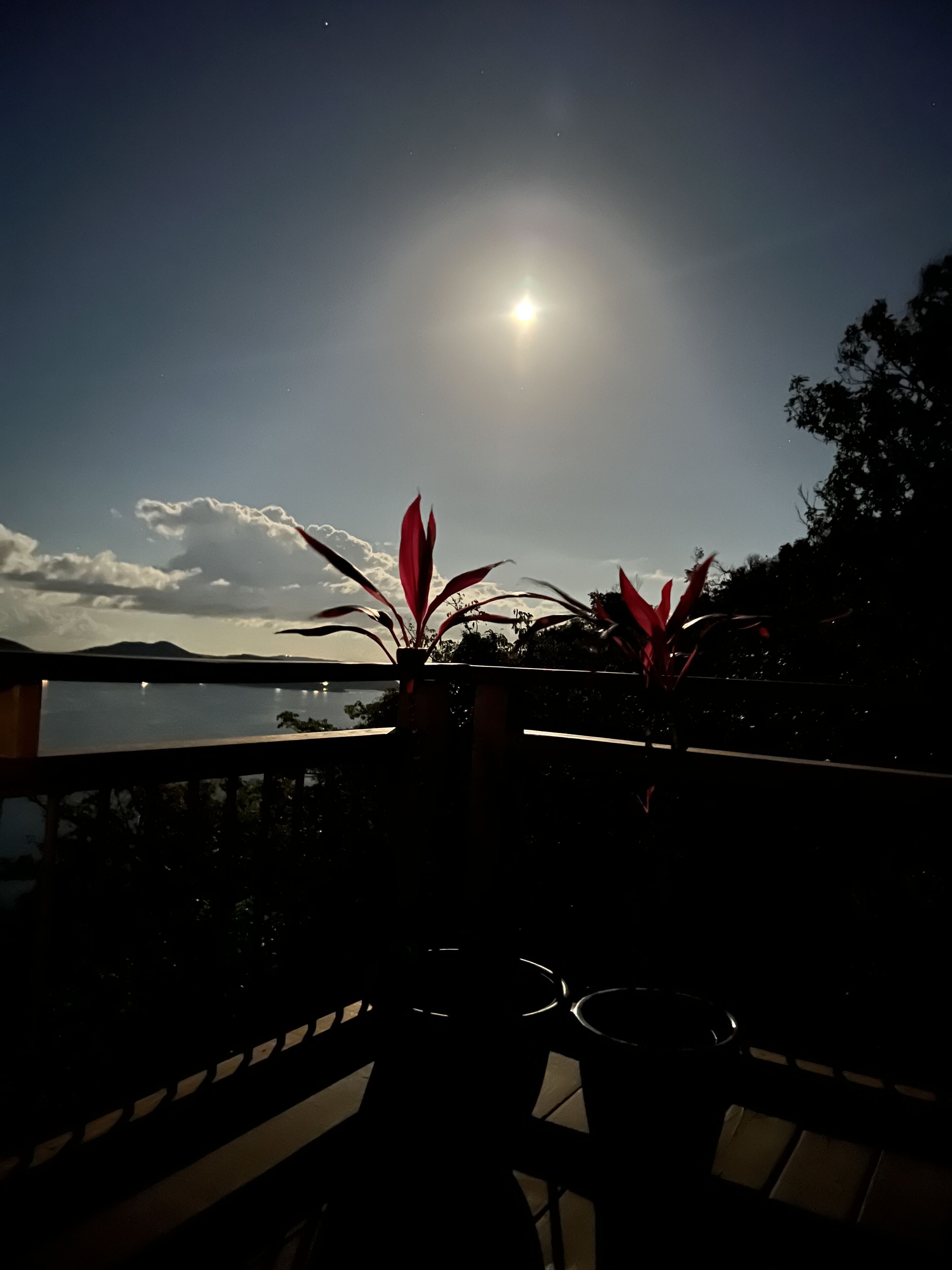 Ein Balkon mit Blick auf Meer und Berge im Abendlicht.