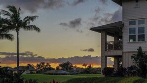 A two-story house with a balcony, surrounded by a well-maintained lawn and palm trees. - Pili Mai 7E - Top Floor 3 - Bed Suite On Golf Course - AC, Pool & Fitness Center (Koloa)