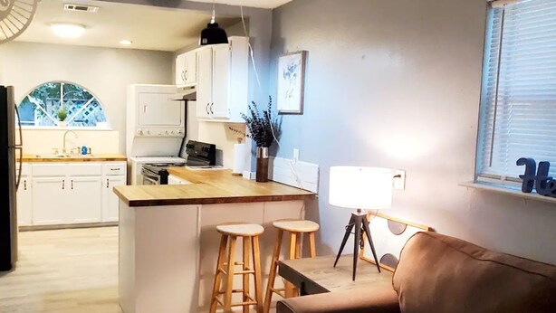 A modern kitchen with a central island, bar stools, and a dining area. - Cute 1 bedroom home, close to Downtown, Beaches and Shopping (Pensacola)