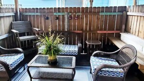 An outdoor patio with wicker furniture, a glass table, and a potted plant. - Cute 1 bedroom home, close to Downtown, Beaches and Shopping (Pensacola)