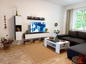 Een moderne woonkamer met een flatscreen televisie, een bank, een salontafel en een decoratieve wandplank.