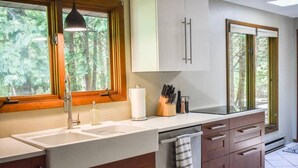 Une cuisine équipée d’un évier à deux bacs, de meubles en bois, d’un porte-serviettes et d’un bloc à couteaux.