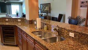 Una cocina con encimeras de granito, electrodomésticos de acero inoxidable e iluminación colgante.
