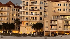 Un hotel de varios pisos con balcones, vista a la playa y terreno arenoso.