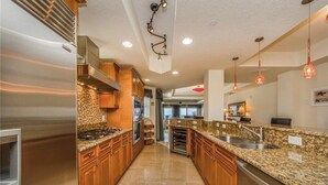 Una cocina moderna con encimeras de granito, electrodomésticos de acero inoxidable e iluminación colgante.