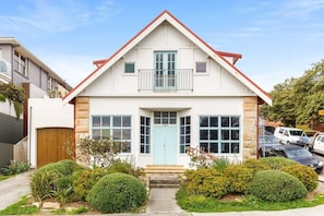 Stunning two-story home with a central entrance, balcony, and beautifully manicured grounds.