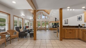 A spacious living area with a high ceiling, large windows, and a kitchen area with wooden cabinets and a fireplace. - Lakeside Living w\sandy beach, gas fireplace -easy 25 minute commute to Portland (Gray)