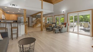A spacious living area with a wooden ceiling, a kitchen with wooden cabinets, and a sliding glass door leading to an outdoor deck. - Lakeside Living w\sandy beach, gas fireplace -easy 25 minute commute to Portland (Gray)