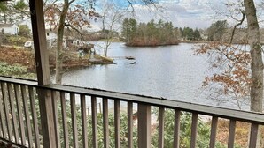 A view from a covered deck overlooking a lake with trees and a small island.