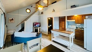 A compact living space with a bed, a dining table, a kitchen area, and a staircase.
