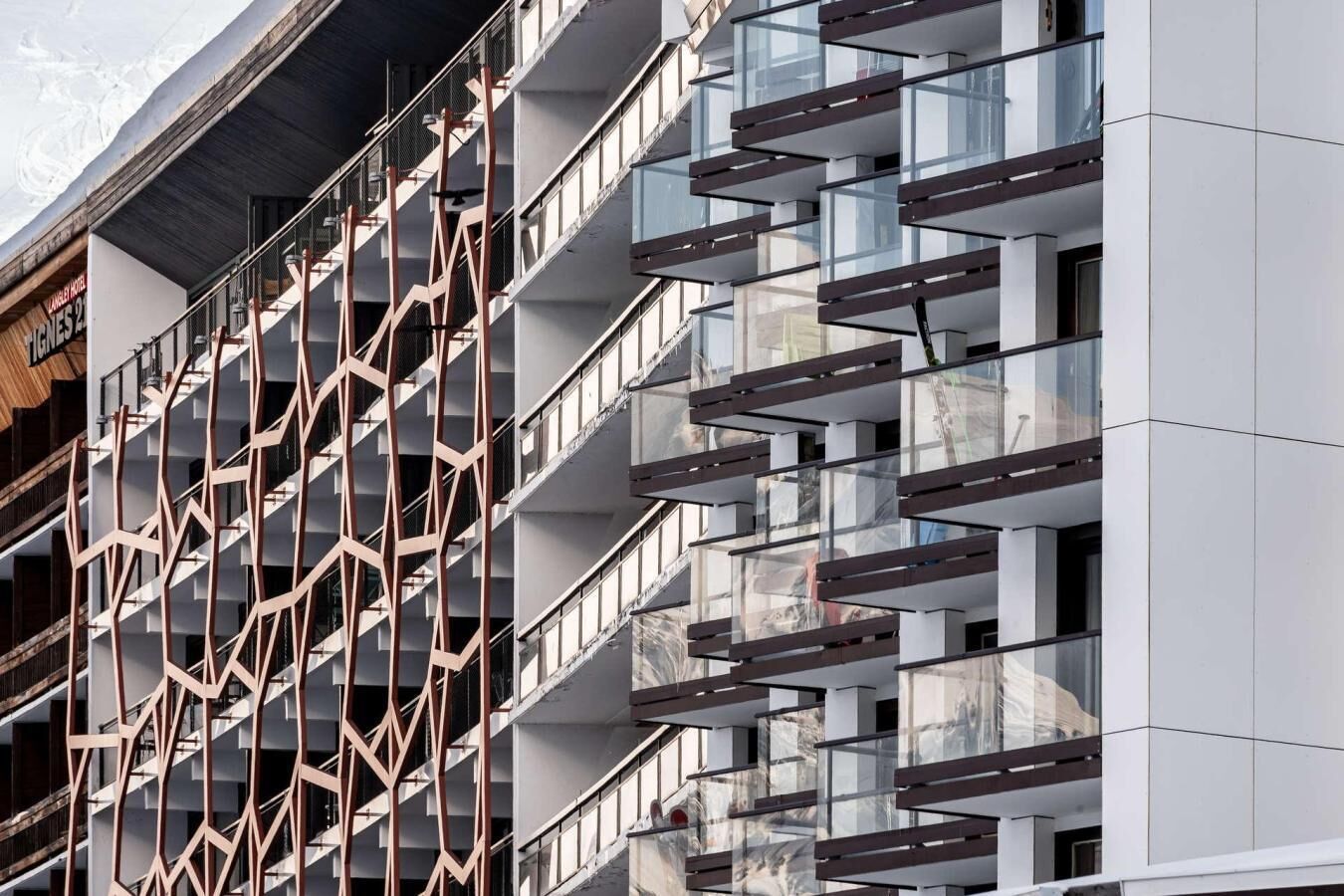 A modern hotel facade with a geometric metal facade and multiple balconies.