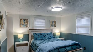Une chambre à coucher avec un lit, des tables de chevet et des œuvres d’art murales.