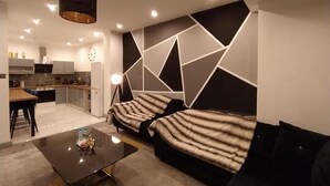 A modern living room with a sofa, a coffee table, and a kitchen in the background. - Black Pearl Luxury Apartments (Blackpool)