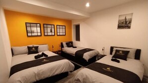 A hotel room with three beds, each with black and white bedding and a logo on the headboard. - Black Pearl Luxury Apartments (Blackpool)