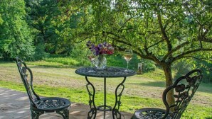 An outdoor patio with a round metal table and two chairs, surrounded by lush greenery. - Idyllic Retreat in The Cotswolds (Chipping Campden)