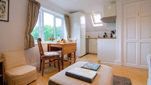 A compact kitchen with a dining area, a small seating area, and a window with curtains. - Idyllic Retreat in The Cotswolds (Chipping Campden)
