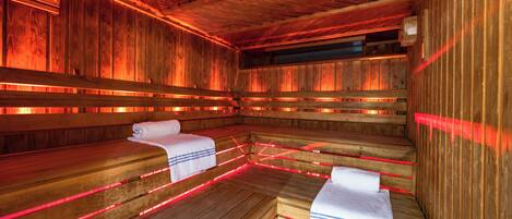 A sauna with wooden benches and red lighting.