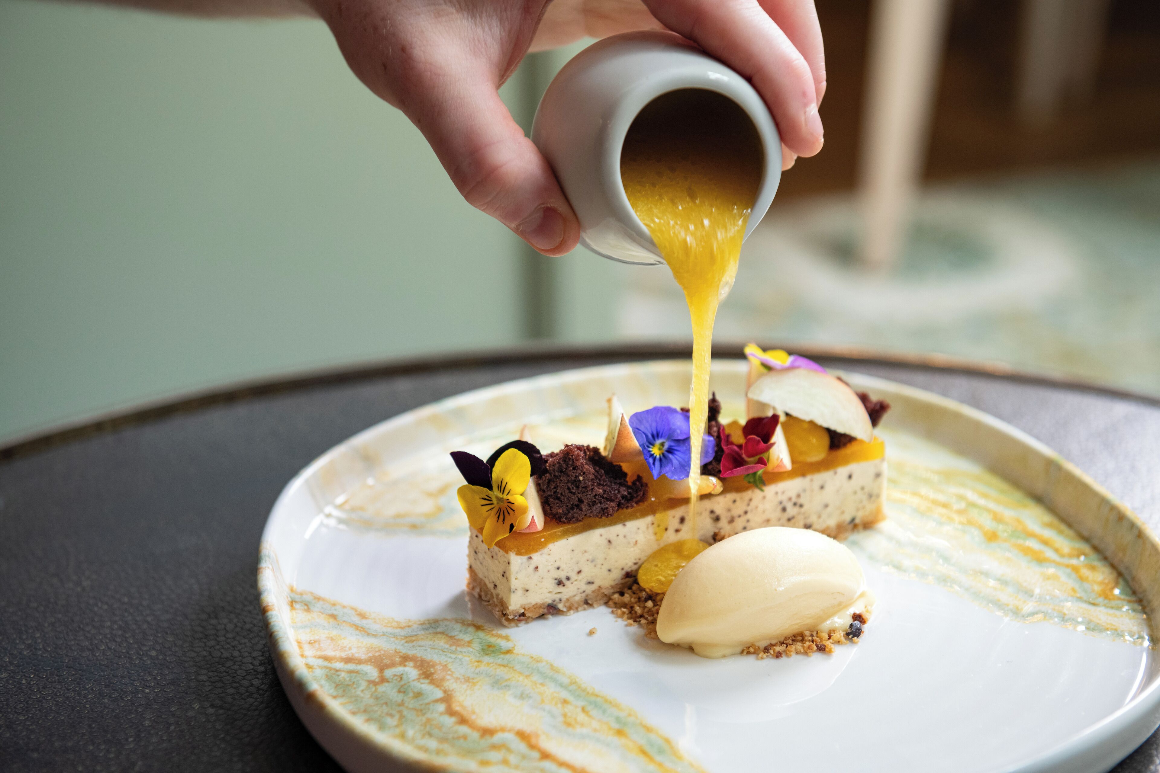 A dessert with a creamy topping being poured onto it.