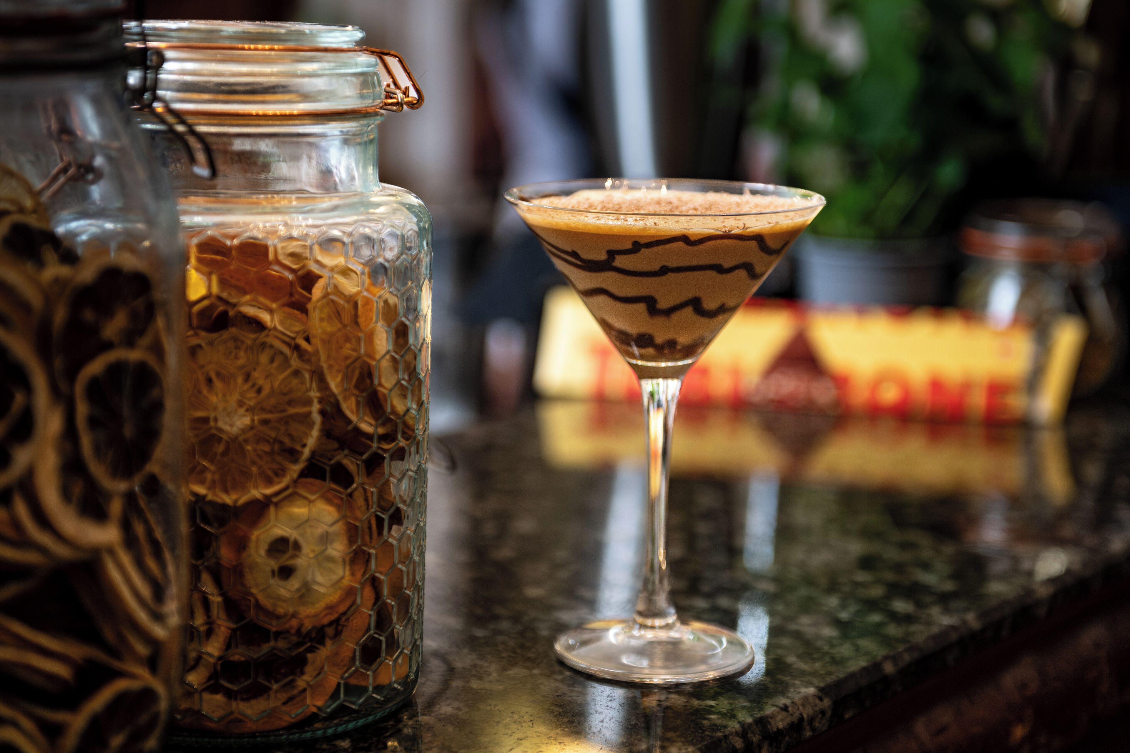 A martini glass with a chocolate swirl on a bar counter.