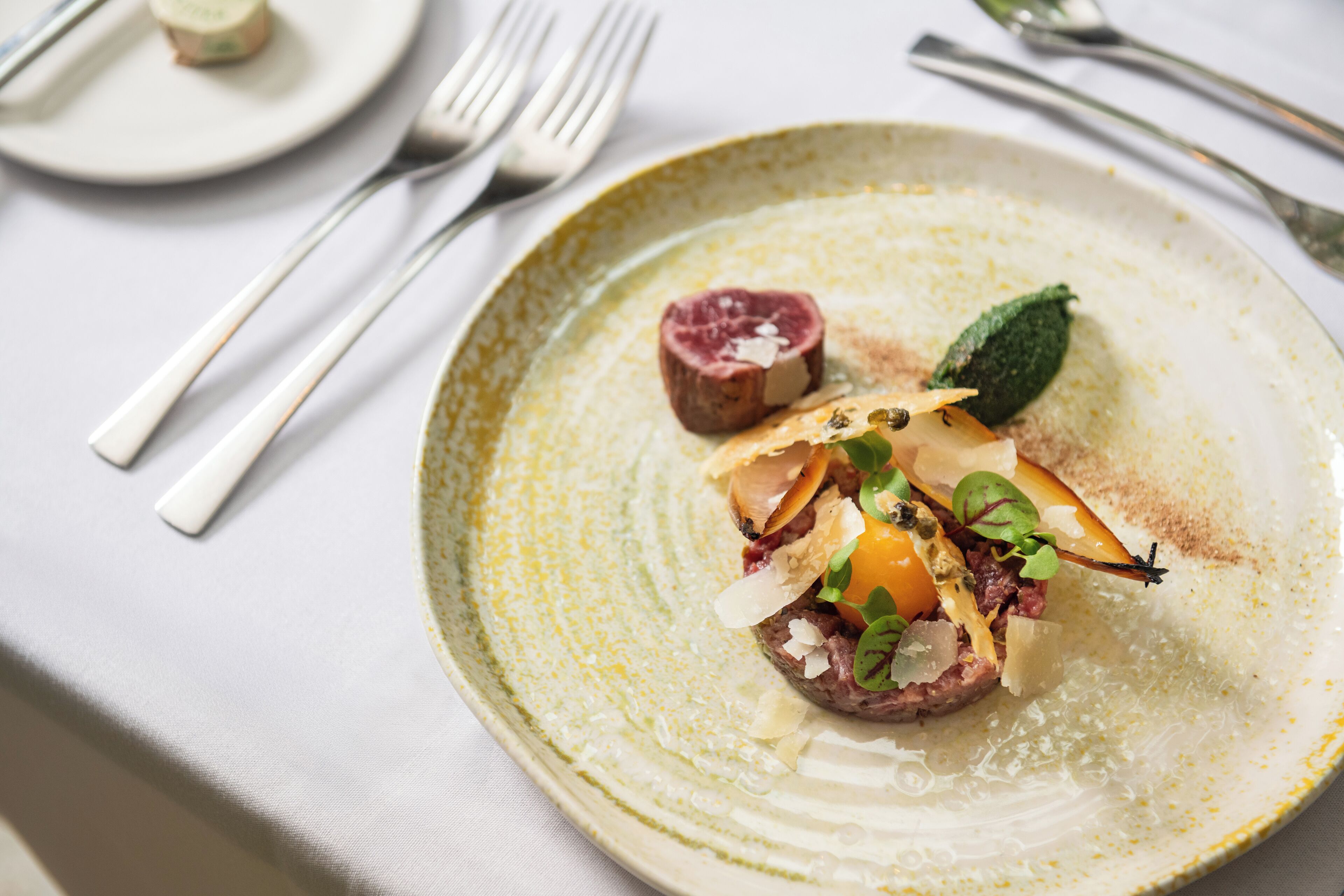 A plate of food with a piece of meat, vegetables, and a garnish on a ceramic plate.