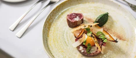 A plate of food with a piece of meat, vegetables, and a garnish on a ceramic plate.