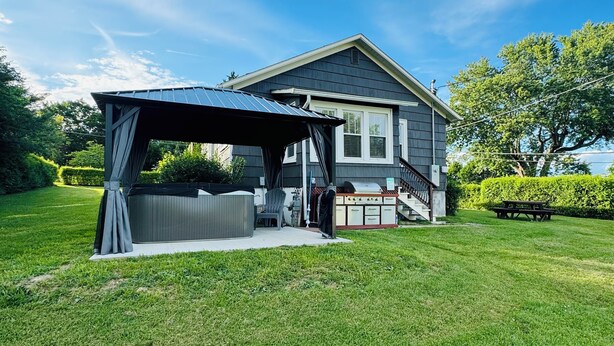 Een huis met een overdekte patio, een veranda en een verzorgd gazon.