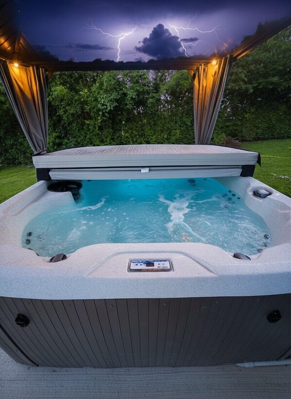 A hot tub with a control panel, surrounded by a wooden deck, set against a backdrop of a stormy sky.