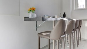 A modern kitchen with a bar area, a vase with flowers, and a window providing natural light. - Voyager House Apartment (Roma)