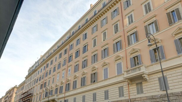 A multi-story building with a uniform facade, numerous windows, and a balcony on the upper floors. - Voyager House Apartment (Roma)