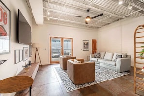 A spacious living area with a sofa, coffee table, and a TV mounted on the wall.