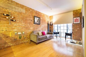 A room with a brick wall, a sofa, a coffee table, and a window. - Central Soho Lofts with Lift,  AirCon & Concierge (Greater London)