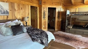 Ein Schlafzimmer in einer Holzhütte mit einem Bett, einer Bank und einem Fellteppich.