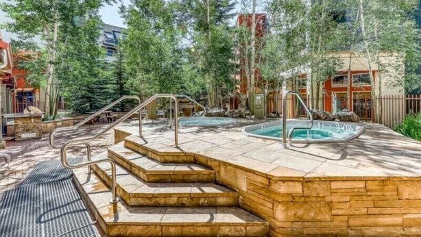A spa area with two hot tubs, stone steps, and a metal railing.