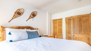 A bedroom with a wooden headboard, a large bed with white and blue bedding, two wall-mounted baskets, and wooden wardrobes.