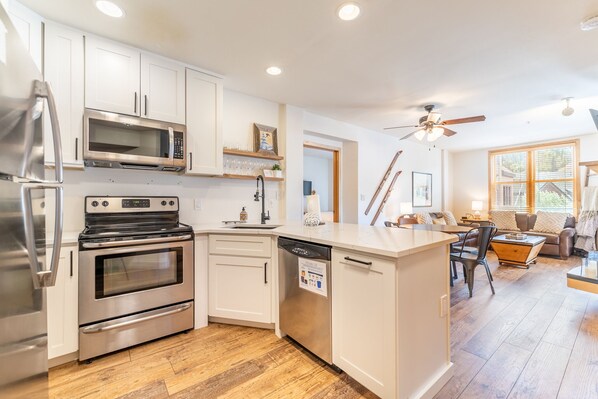 A modern kitchen with stainless steel appliances, white cabinetry, and a wooden floor. - 3 Minute Walk to Gondola w/ hot tub, pool, sauna! (Keystone)