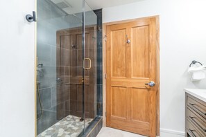 A bathroom with a glass-enclosed shower, a wooden door, and a white sink with a towel rack. - 3 Minute Walk to Gondola w/ hot tub, pool, sauna! (Keystone)