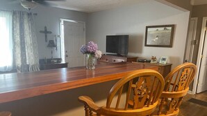 A wooden dining area with a TV, a vase of flowers, and a framed picture on the wall. - Cozy, Clean, and Convenient (Parsons)