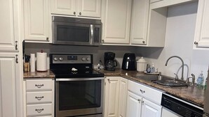 A modern kitchen with white cabinets, stainless steel appliances, and a granite countertop. - Cozy, Clean, and Convenient (Parsons)