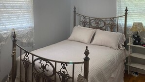 A bedroom with a four-poster bed, a chandelier, and a nightstand with a lamp. - Cozy, Clean, and Convenient (Parsons)