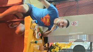 Two people seated at a table with a yellow tablecloth, a plate of food, and a vase of flowers. - Thai smile serviced Appartments (Pattaya)