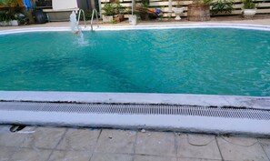 Uma piscina com superfície de água azul cristalina, escada de acesso e área do deck revestida com azulejos.