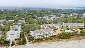 A coastal residential area with multiple houses, a swimming pool, and a beach in the foreground. - Beach Club Villa 30 - Oceanfront! Pool! Walkout! (Isle of Palms)