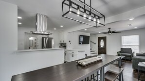 A modern kitchen with a central island, white cabinetry, and a stainless steel range hood. - Luxury Home w/ Volleyball, Golf, & Sports (Irving)