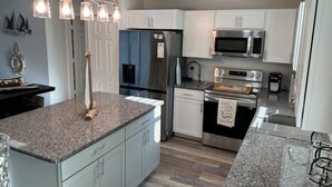 A modern kitchen with granite countertops, stainless steel appliances, and a central island.