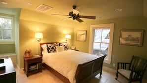 Quarto com cama, mesas de cabeceira, ventilador de teto e janela.