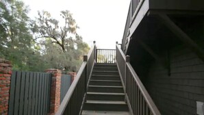 Escada que leva a um edifício com parede de tijolos e guarda-corpo de metal.