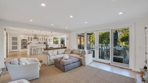 Un salon spacieux, doté d’un grand canapé, d’une table basse et offrant une vue sur la terrasse extérieure.
