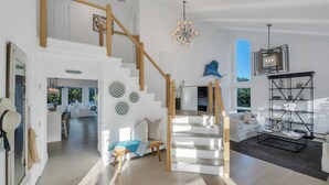 Un vaste espace de vie comprenant un escalier, un coin repas et une vue sur l’extérieur.