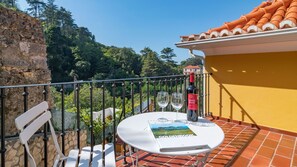 Un balcón con una mesa, dos sillas, una botella de vino y un libro titulado 'Goldenbrook'.